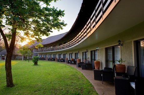 Curved thatched wing and lawns at A'Zambezi River Lodge, Victoria Falls
