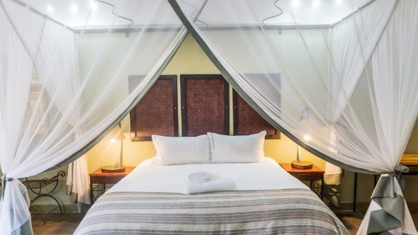 Guest room with a four-poster bed at Nguni Guest Lodge