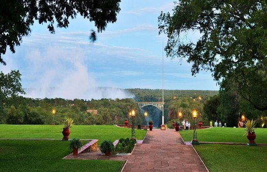 Lawns of The Victoria Falls Hotel with the spray of the falls beyond