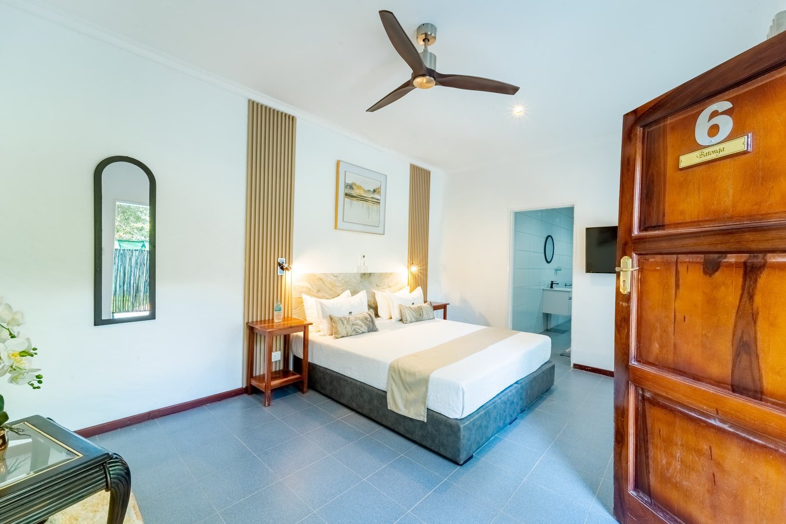 Double room with a mirror and ceiling fan at Murugare