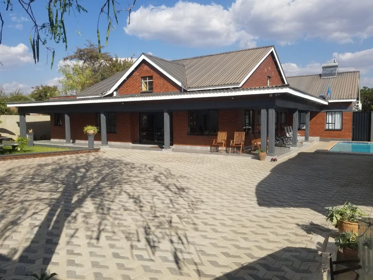 Brick house with covered veranda and swimming pool at Rupiya House