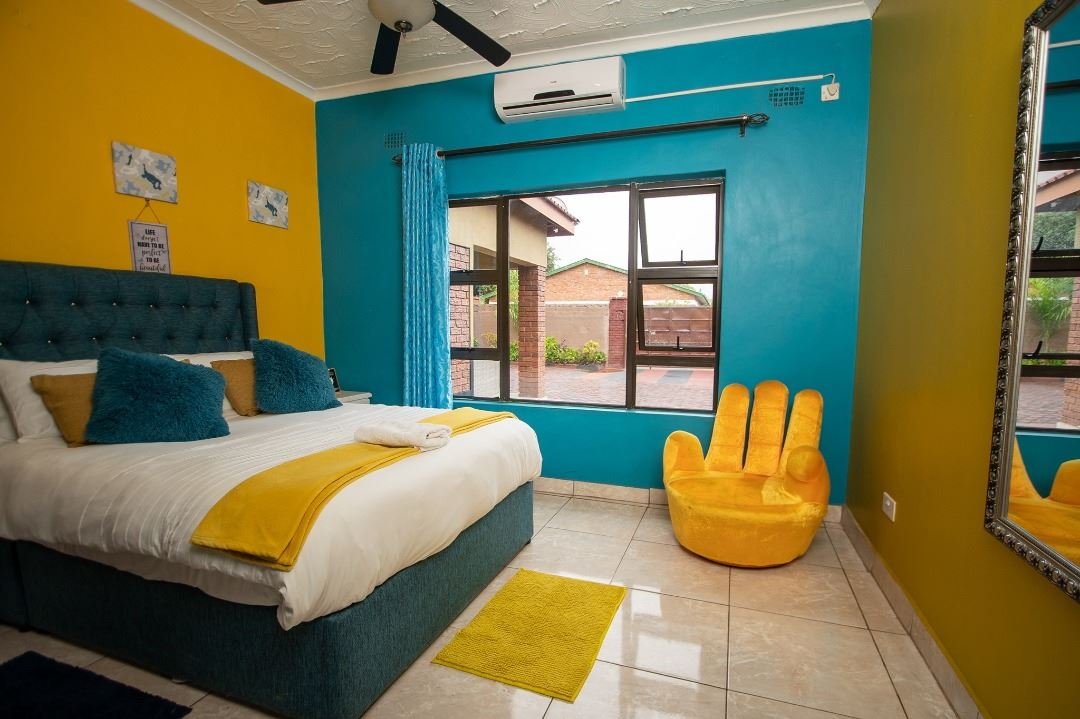 Brightly painted double bedroom with a ceiling fan at Sweet Home
