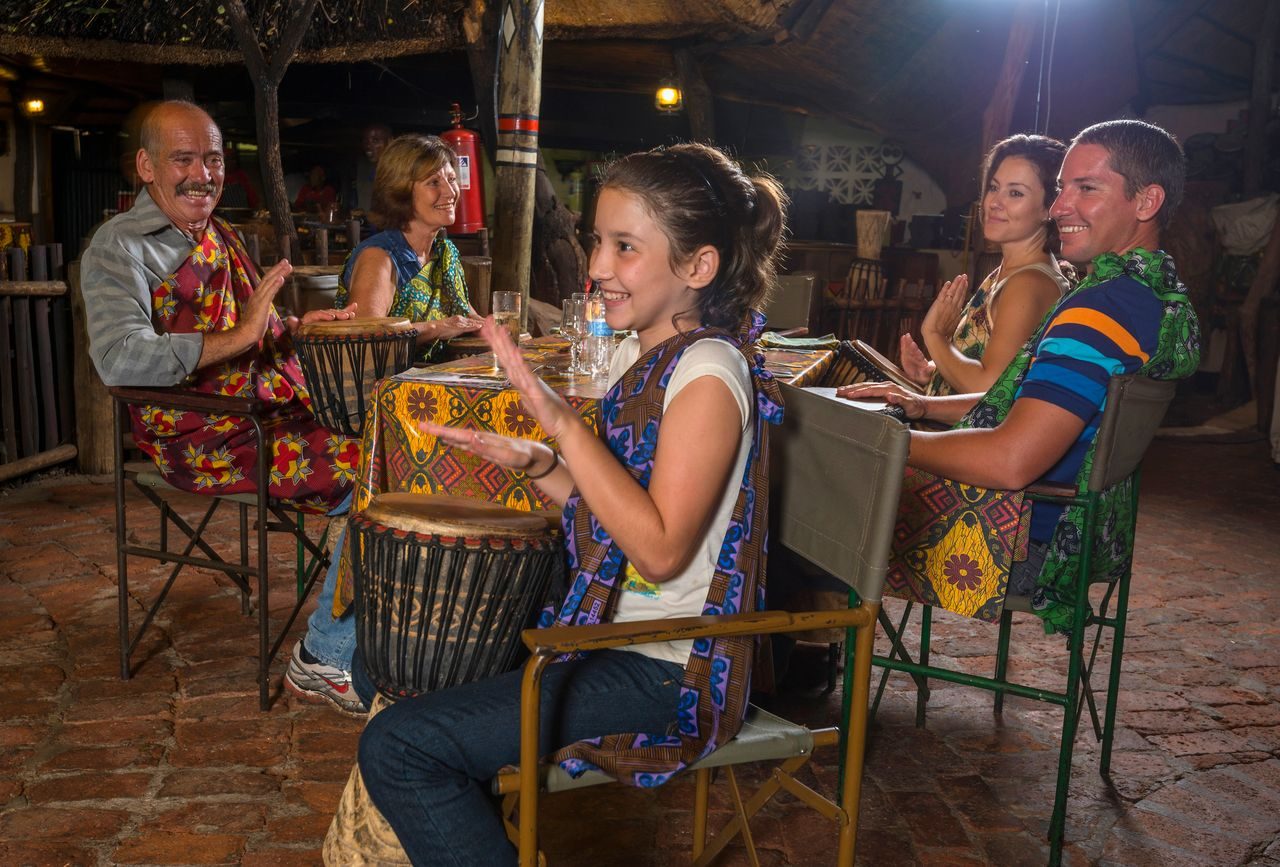 A guest playing a djembe drum at her table during the Boma drum show
