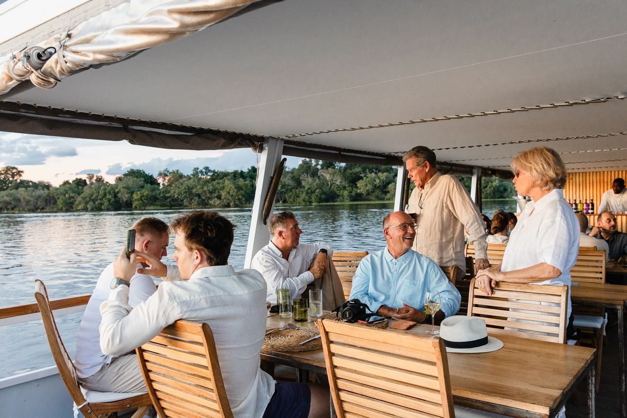 Guests with drinks at tables on the dinner cruise deck
