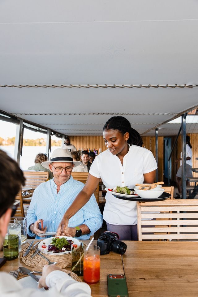 A waiter serving a plated course on the Zambezi dinner cruise