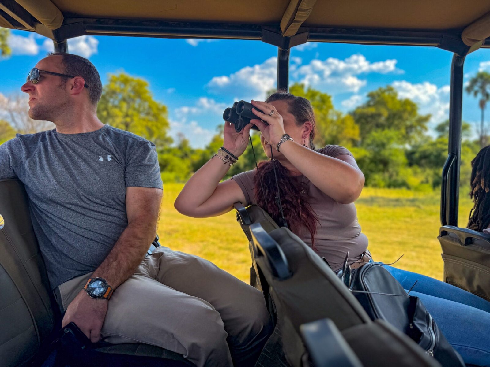 Guests with binoculars and a camera on a Zambezi National Park game drive