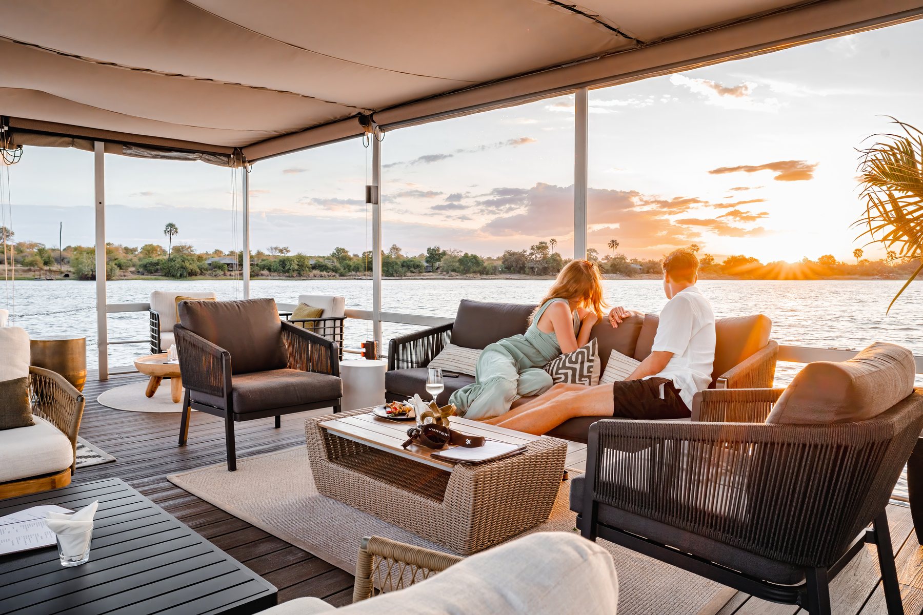 Guests on the deck of a Zambezi sunset cruise boat as the sun sets near Victoria Falls