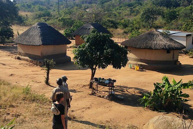 Village homestead with thatched huts and a guide near Victoria Falls
