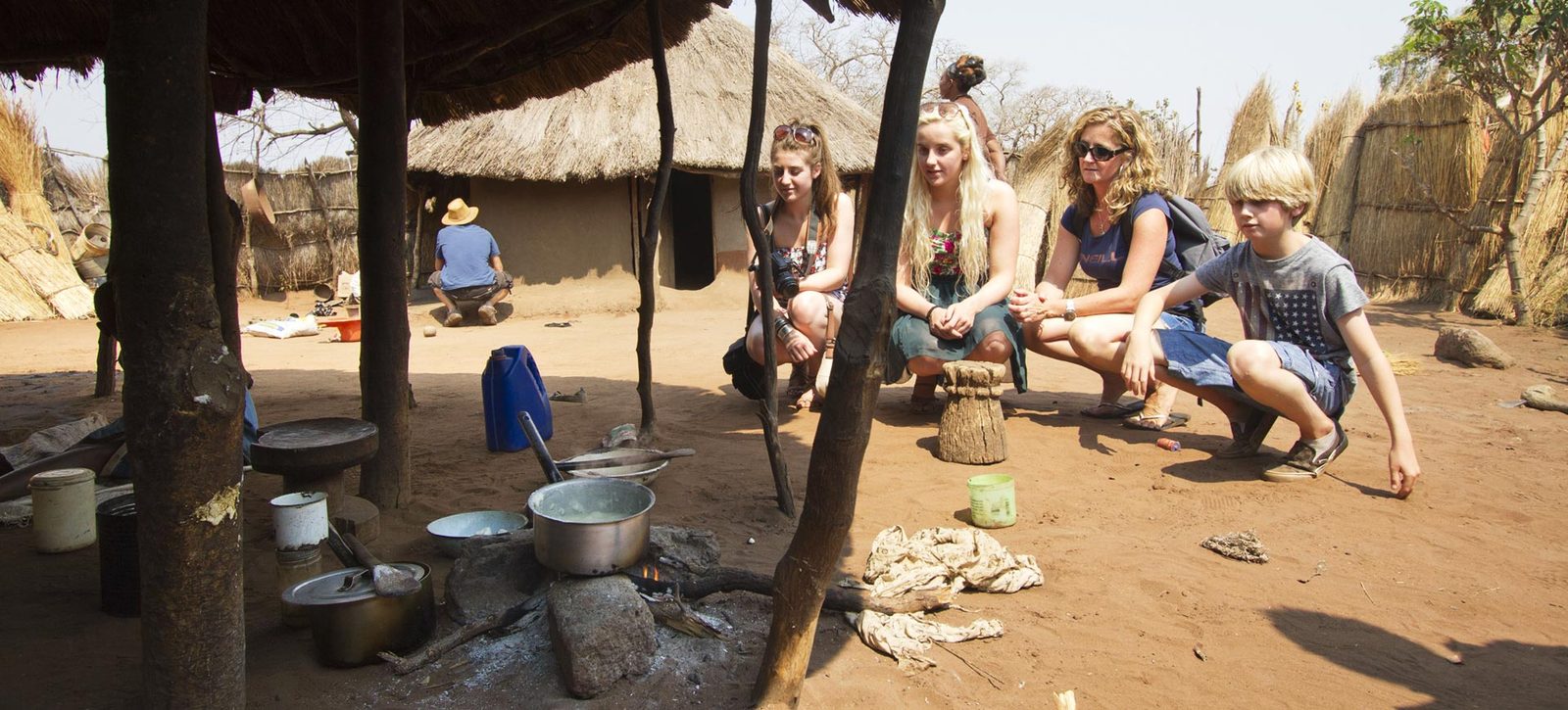 Visitors sitting with a guide at a village homestead near Victoria Falls