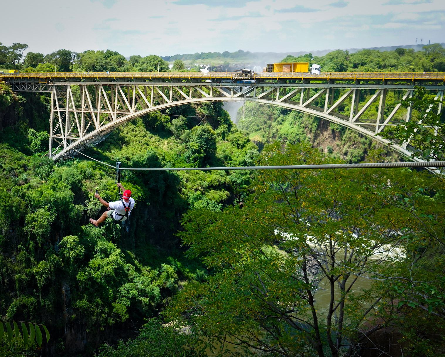 Zip line rider crossing the Batoka Gorge with the Victoria Falls Bridge behind