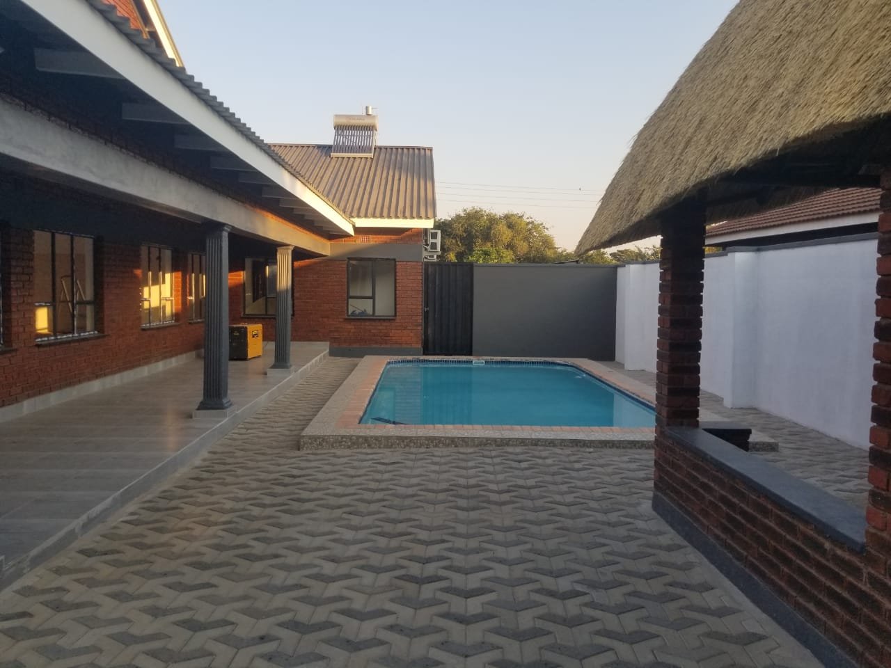 Thatched house and swimming pool at Rupiya House, Victoria Falls
