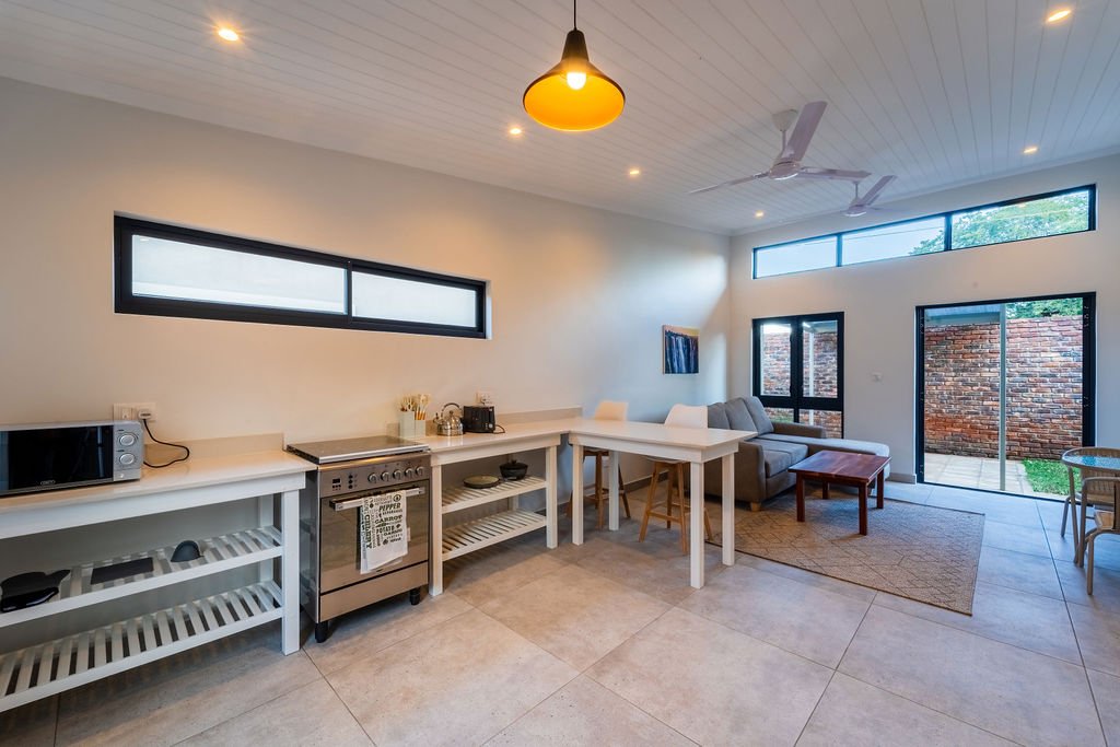 Kitchen with open shelving and a dining table in a Pods villa