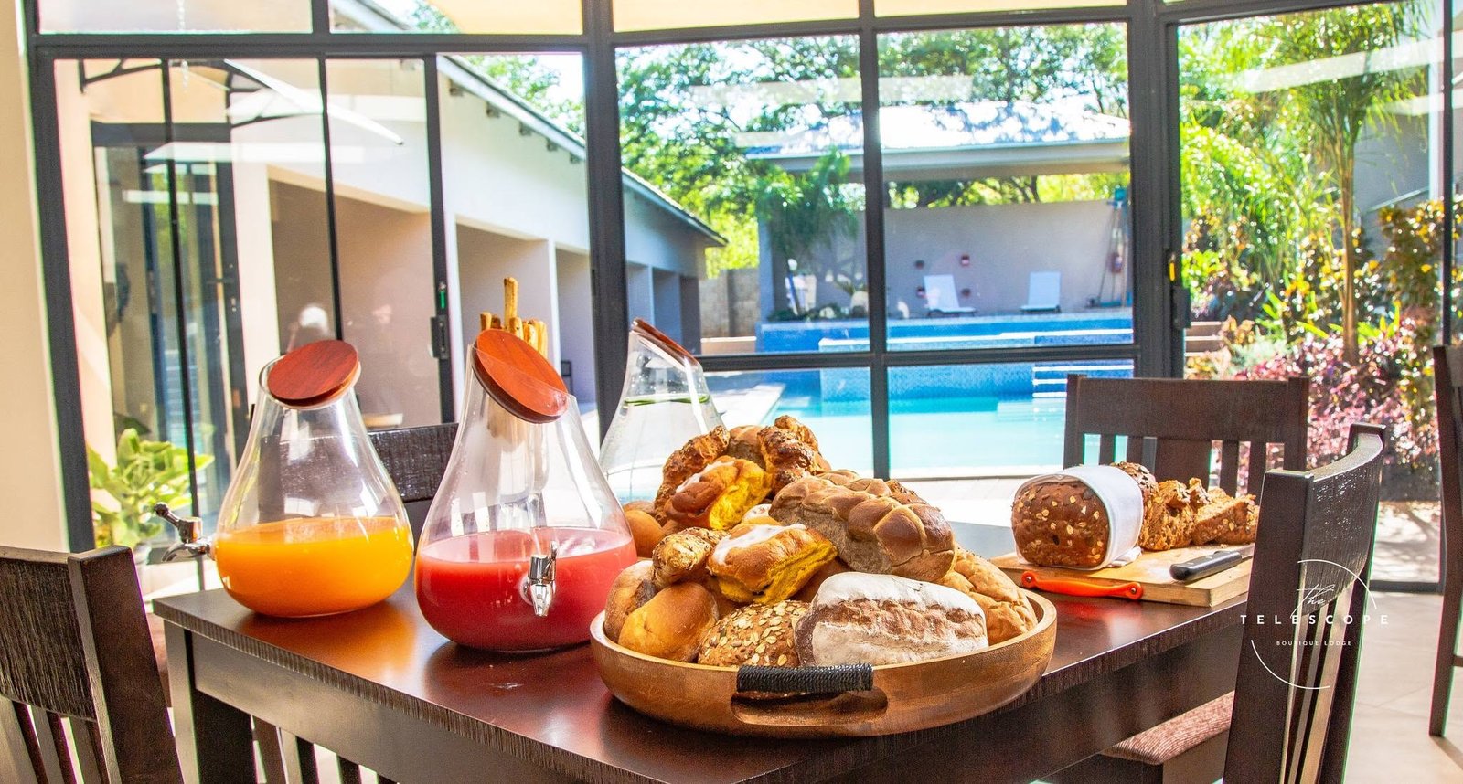Breakfast table with fresh pastries and juice overlooking the pool at The Telescope Boutique Lodge